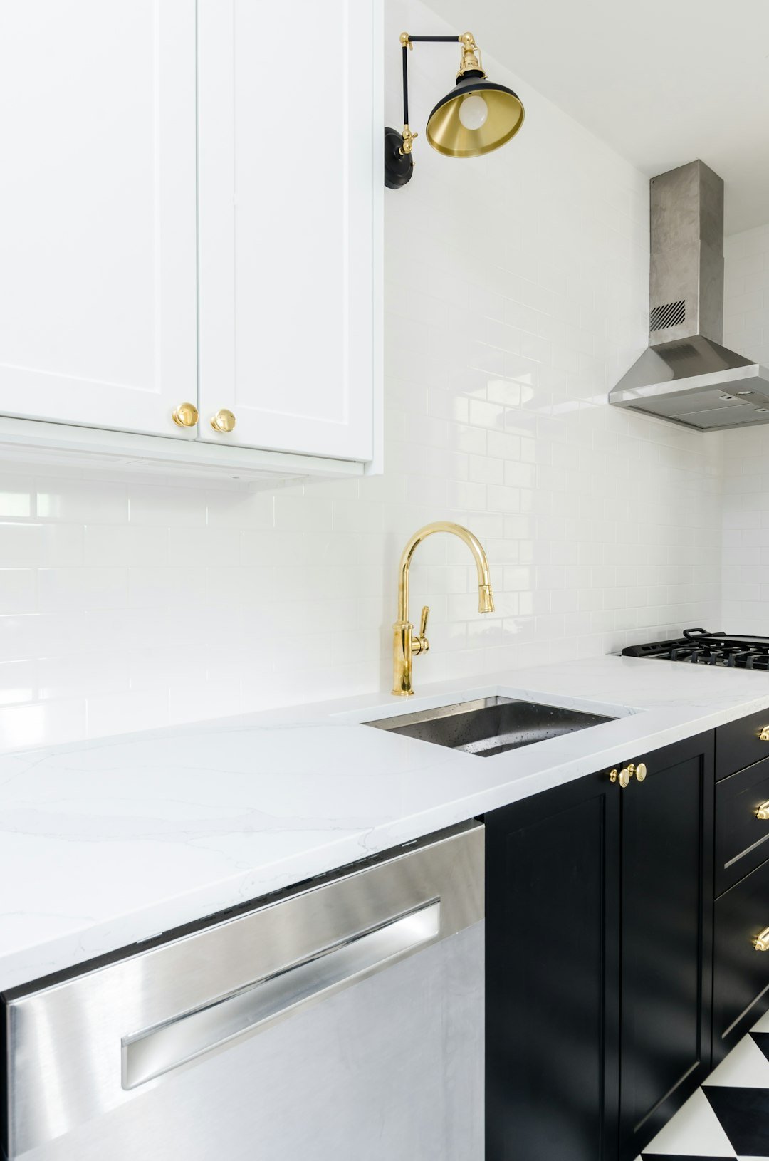 White & Black kitchen with gold faucets and gold finishings. Black & white checkered floor. Marble countertop. Black kitchen cabinets. White kitchen cabinets.